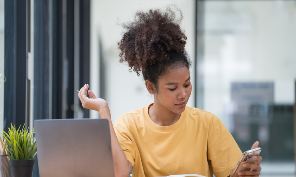 Woman using smartphone and laptop to budget