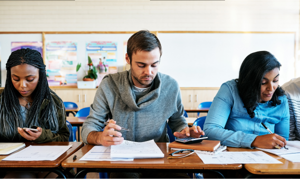 Three young adults in a classroom learning budgeting and financial literacy skills