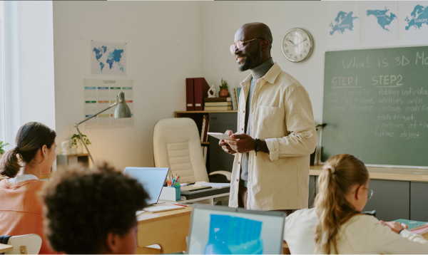 African american male teacher teaching students in a classrooms with their laptops open