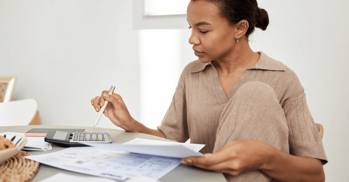 Minimal side view portrait of young Black woman doing taxes at home and using calculator, copy space